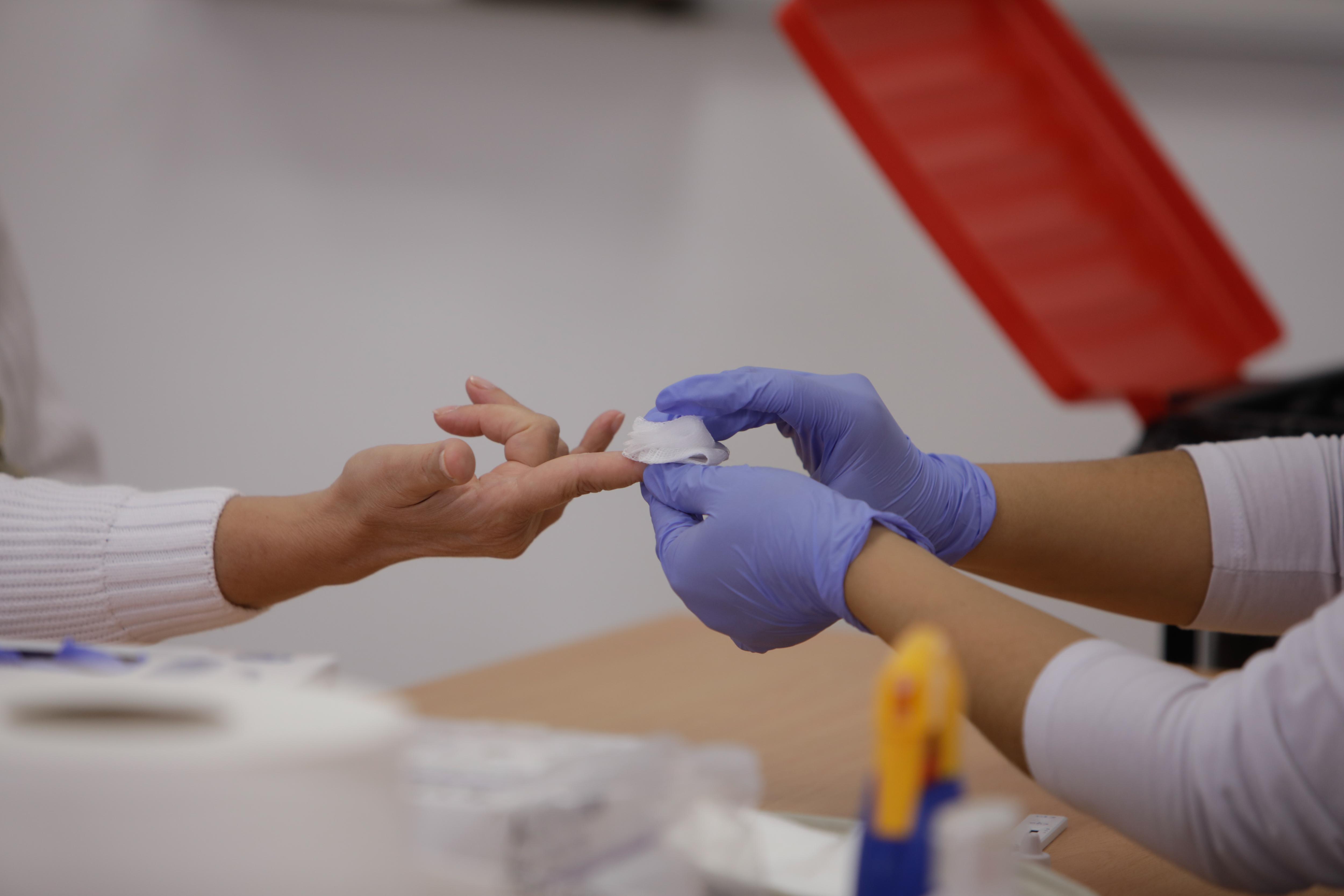 Personal sanitario de Cruz Roja saca sangre de un dedo a una persona para realizar el test rápido de detección de anticuerpos / EP