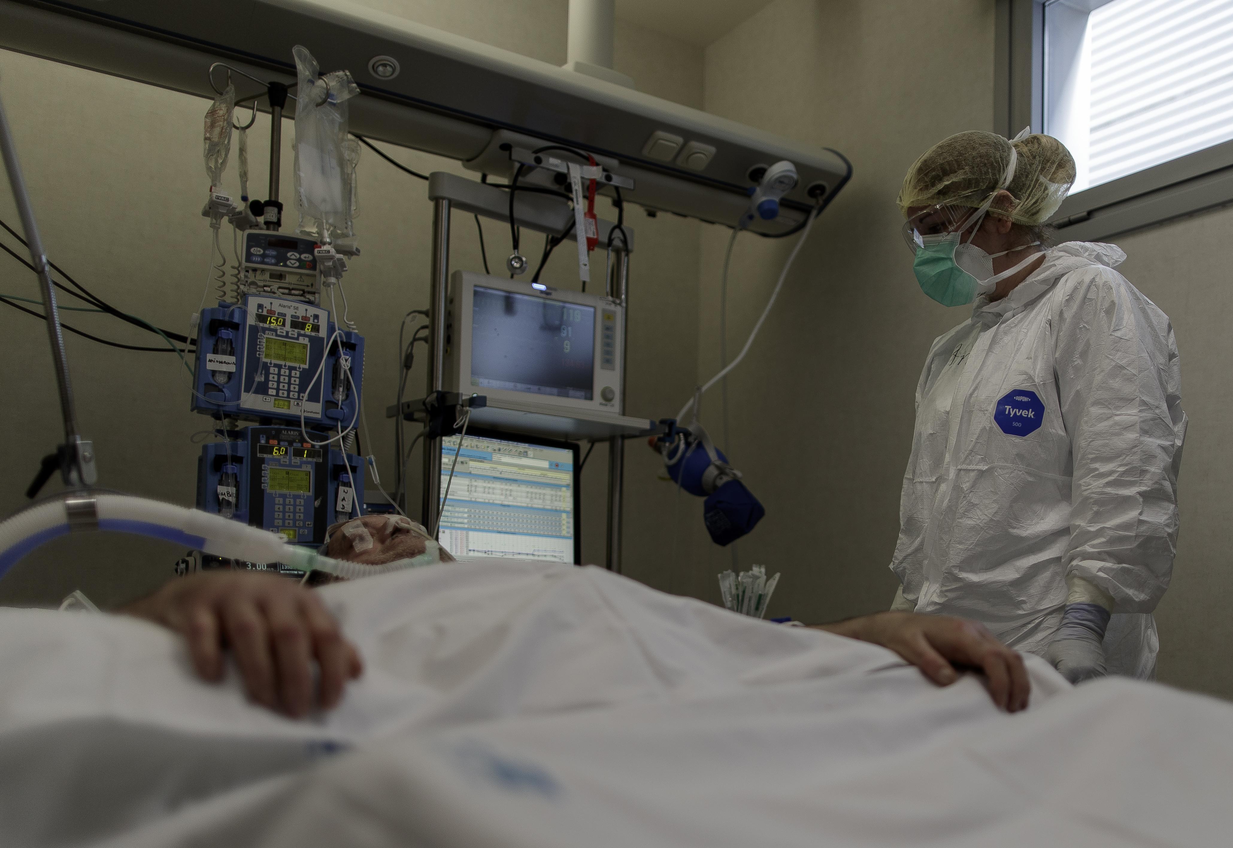 Personal sanitario totalmente protegido atiende a un paciente ingresado en la Unidad de Cuidados Intensivos del Hospital Infanta Sofía en San Sebastián de los Reyes. EP.