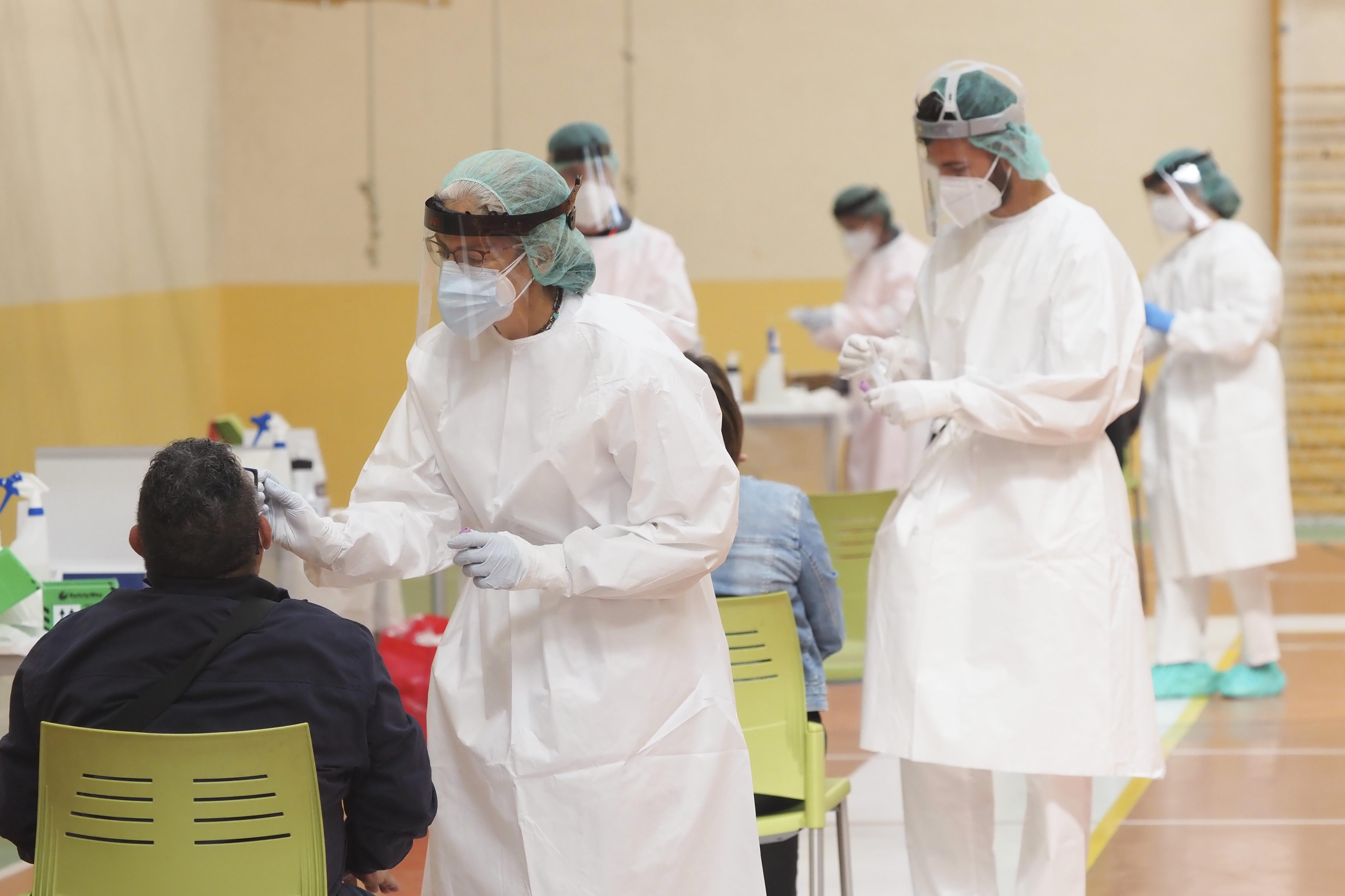 Una sanitaria toma muestras a un hombre a través de un frotis de nariz durante la realización de test de antígenos.