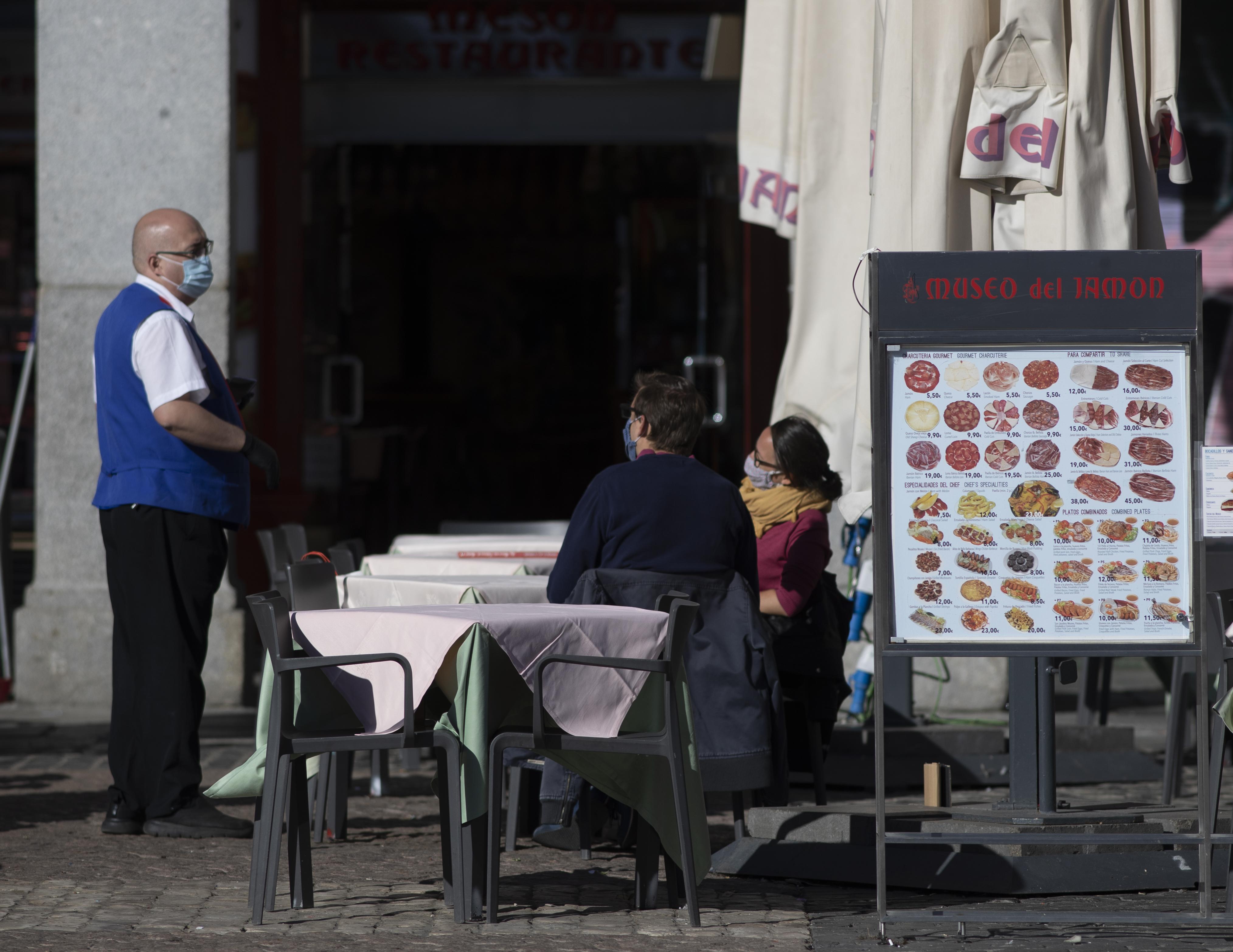 Un camarero atiende a los clientes en la Plaza Mayor en el primer día del estado de alarma en Madrid. Europa Press. 