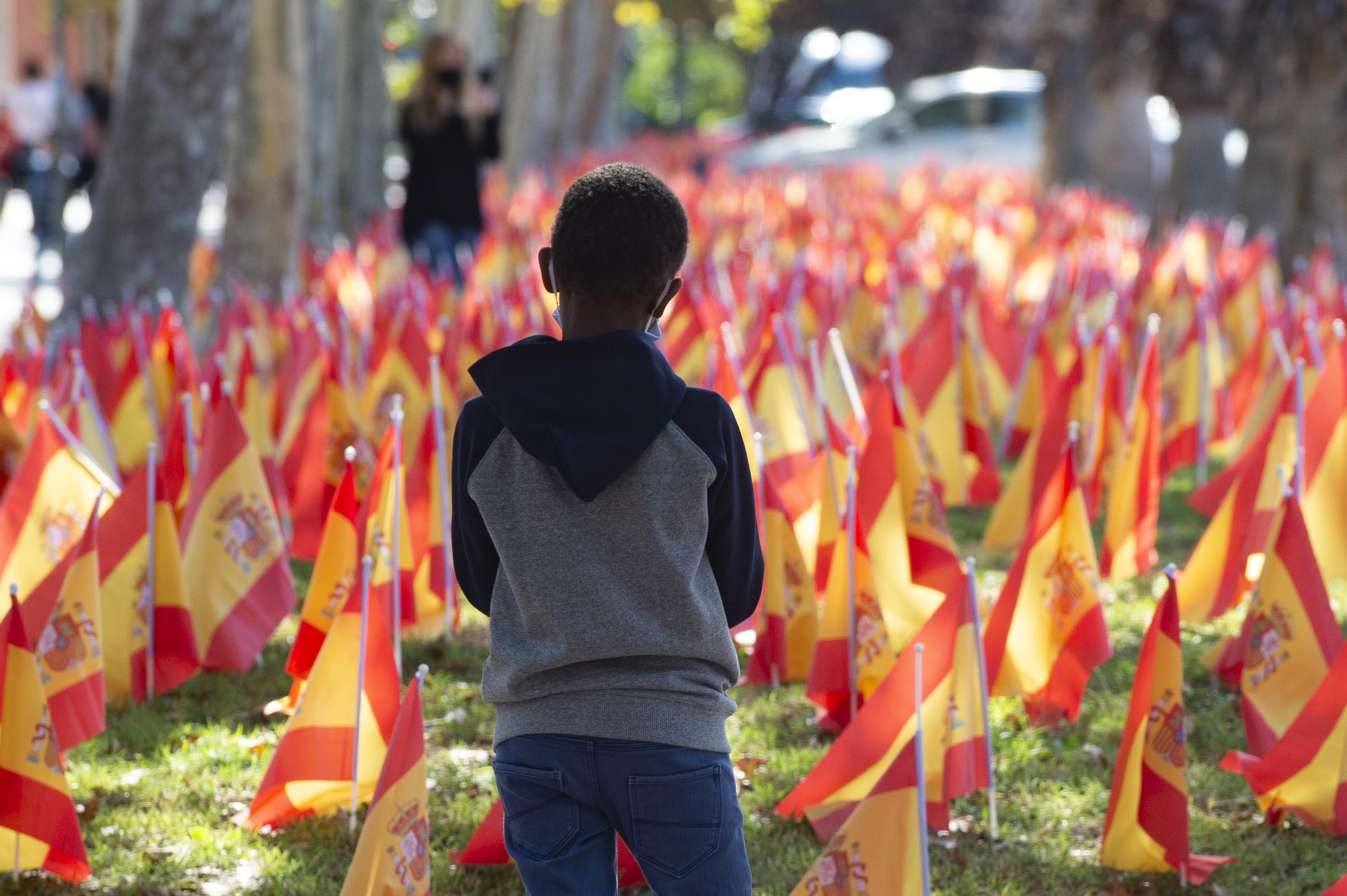 Un niño observa las banderas de España en el Parque Isidoro Medina de Murcia